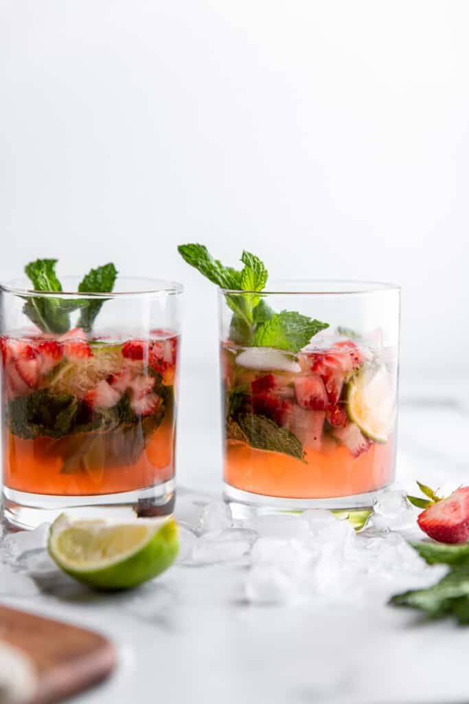 two Strawberry Mojito on a table with mint leaves
