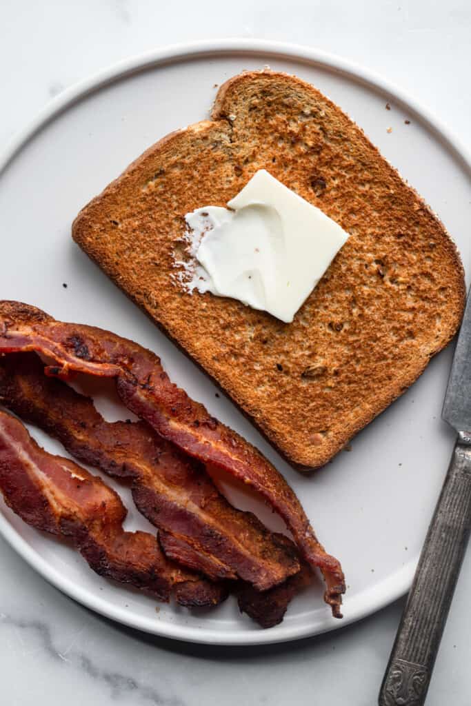 Air Fryer Toast with butter on top and bacon on the side