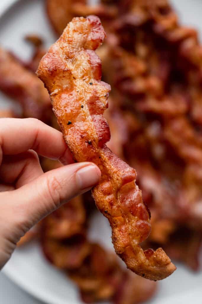 a slice of air fryer bacon being held up